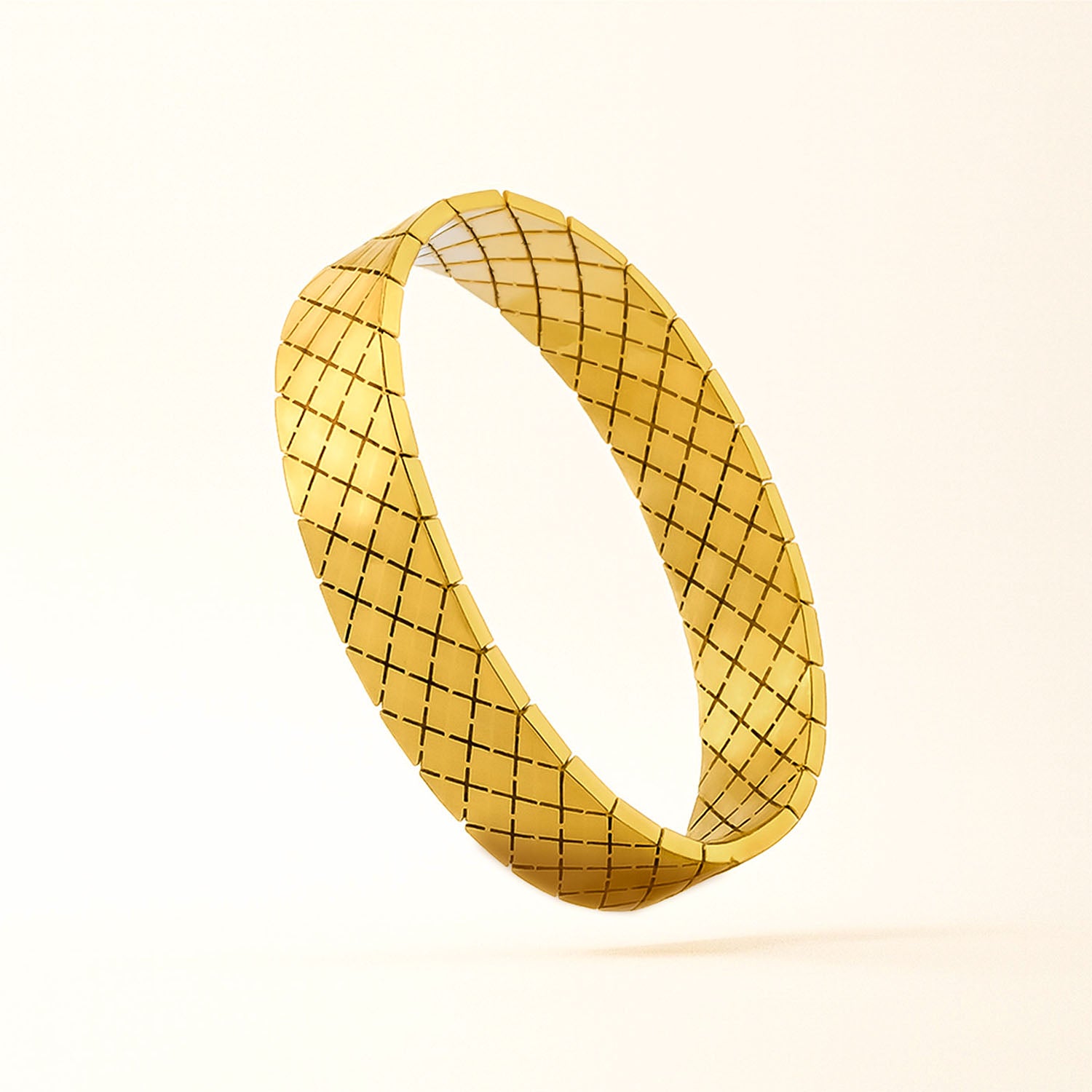 Gold bracelet with a textured pattern on a beige background